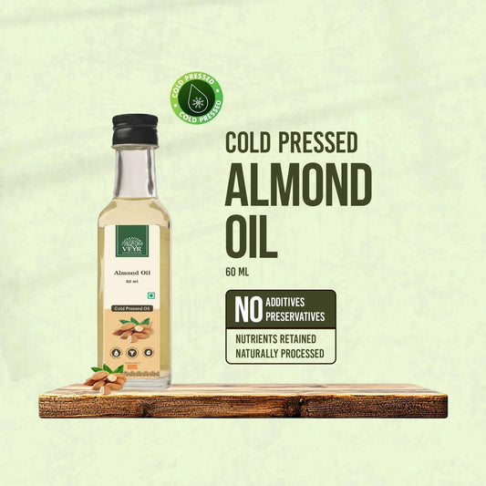Bottle of premium cold pressed almond oil with almonds and green leaves for skincare and cooking benefits