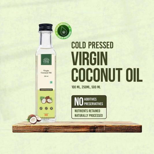 Bottle of premium cold pressed virgin coconut oil with fresh coconuts and green leaves