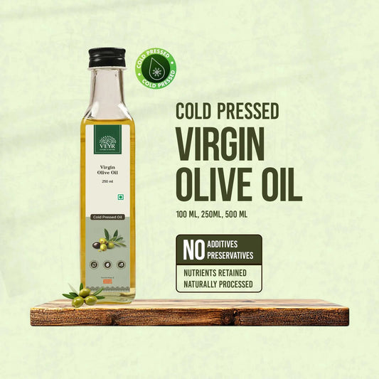 Bottle of premium cold pressed virgin olive oil with fresh olives and a wooden spoon on rustic wooden background